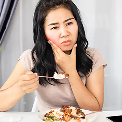 顎の痛みに耐えながら食事する女性